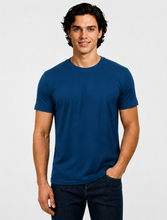 Load image into Gallery viewer, A man wearing a solid navy blue crew-neck t-shirt and dark blue jeans, standing against a light gray studio background.