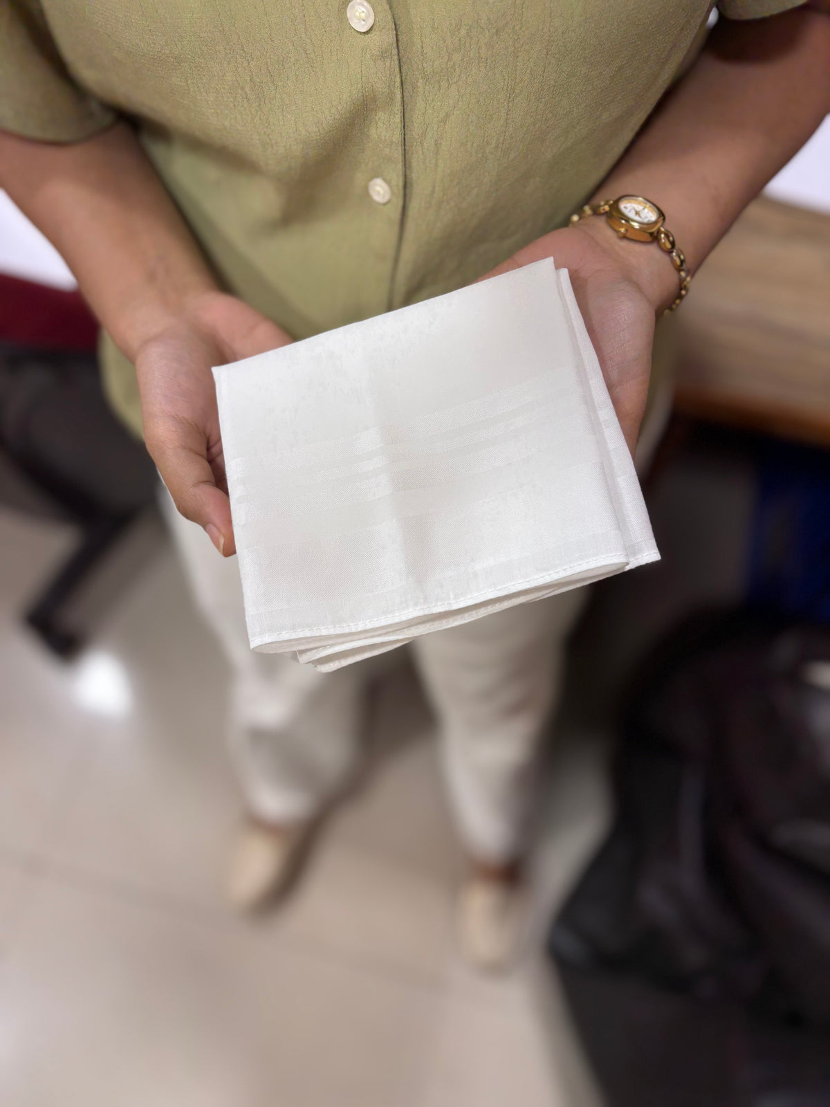 A folded Heelium handkerchief held in the hands, ready for everyday use